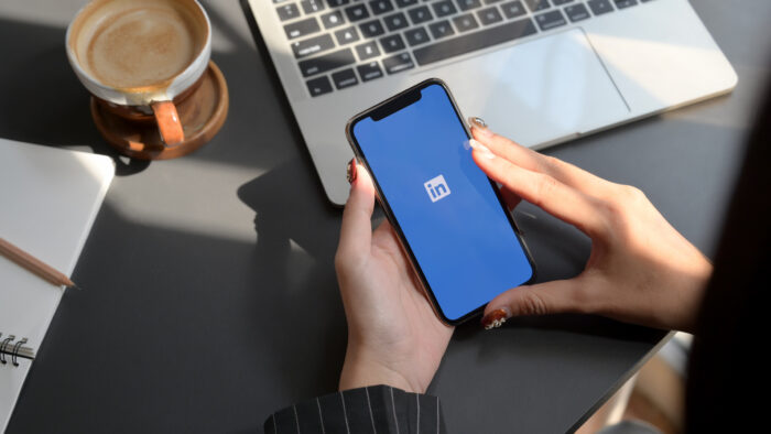 CHIANG MAI, THAILAND – JANUARY 31, 2020 : female holding iPhone with LinkedIn screen. LinkedIn helps build resume and look for a new job